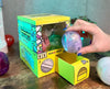 Sugoi Mart mini yellow colored gachapon box with purple capsule toy.